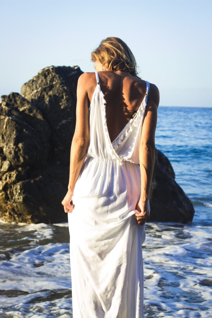 Vrou in wit rok op die strand